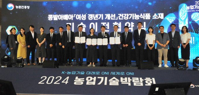 곽도원 국립식량과학원(왼쪽에서 8번째)과 안호근 한국농업기술진흥원장(왼쪽에서 7번째), 도선희 건국대 교수(왼쪽에서 9번째), 이희준 현대바이오랜드 대표(오른쪽에서 8번째)가 이달 11일 일산 킨텍스에서 ‘콩 발아배아 여성 갱년기 개선 건강기능식품 소재 기술이전 협약식’ 후 참석한 관계자들과 기념 촬영하고 있다.